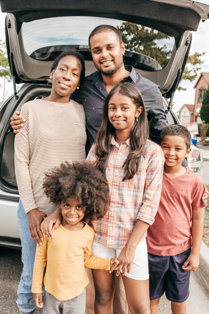 stock photo of family standing in front of car