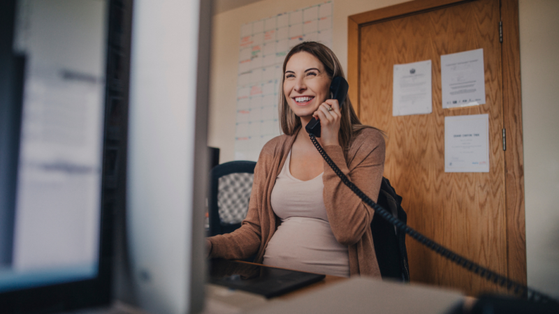 stock photo of pregnant woman on phone in office setting